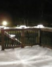 Low voltage deck lighting is displayed above underneath a few inches of snow.